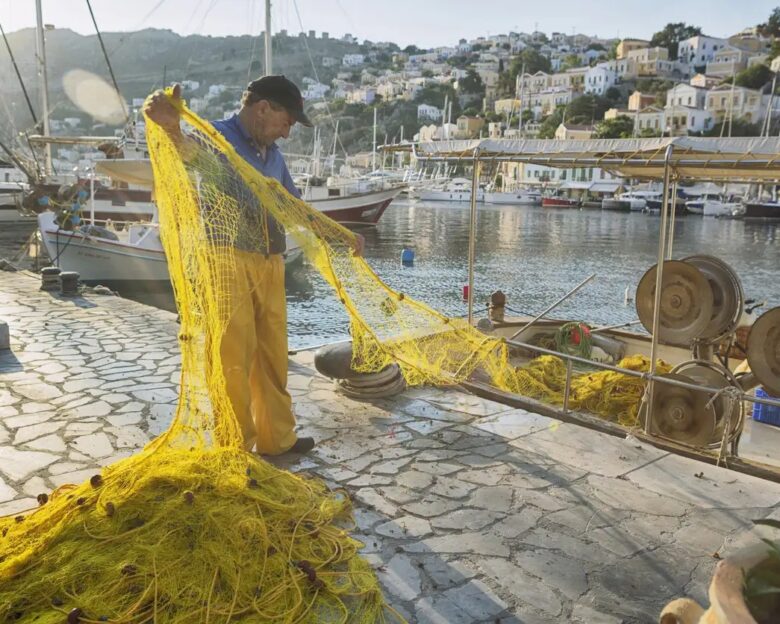 Symi, Greece - Greek fisherman working in Symi Harbour. Symi is a Greek island and municipality. The island has 2,580 inhabitants, mostly engaged in tourism, fishing, and trade.
