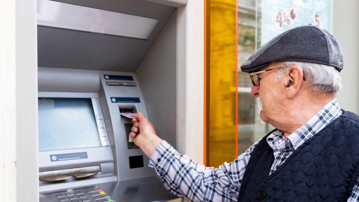 elderly man inserting credit card to ATM outdoor