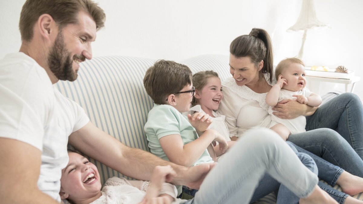 Family at home with four children having fun together, laughing and smiling