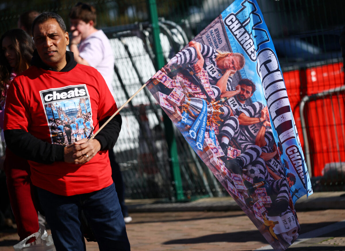 Soccer Football - Premier League - Liverpool v Manchester City - Anfield, Liverpool, Britain - October 11, 2026 A Liverpool fan holds a flag related to the Manchester City's Premier League charges outside the stadium before the match REUTERS