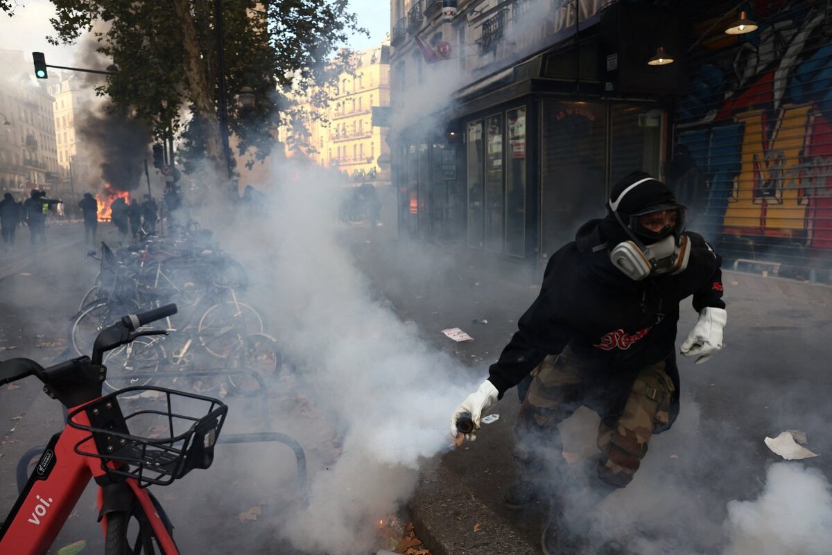 A masked protester runs holding a tear gas canister amid clashes during a day of demonstrations against the cost of living and rising fuel prices in Paris as part of nationwide protests called by the "Yellow Vests" movement, joined by French high school and university students, teachers and parents demanding better school conditions and government action, as well as labour unions, workers, farmers and retirees, France, October 17, 2026. REUTERS