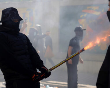 A protester uses a firework against police during clashes in Tirana, Albania, Wednesday, Oct. 14, 2026, joining a demonstration organized by the Flamingo protest movement demanding the resignation of Prime Minister Edi Rama.