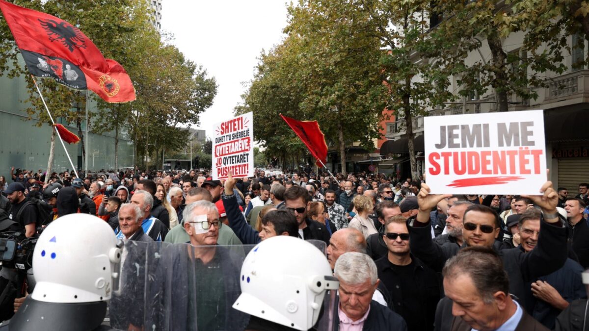 Διαδηλωτές ανεμίζουν σημαίες και κρατούν πλακάτ, καθώς συγκεντρώνονται απέναντι από αστυνομικούς στα Τίρανα της Αλβανίας