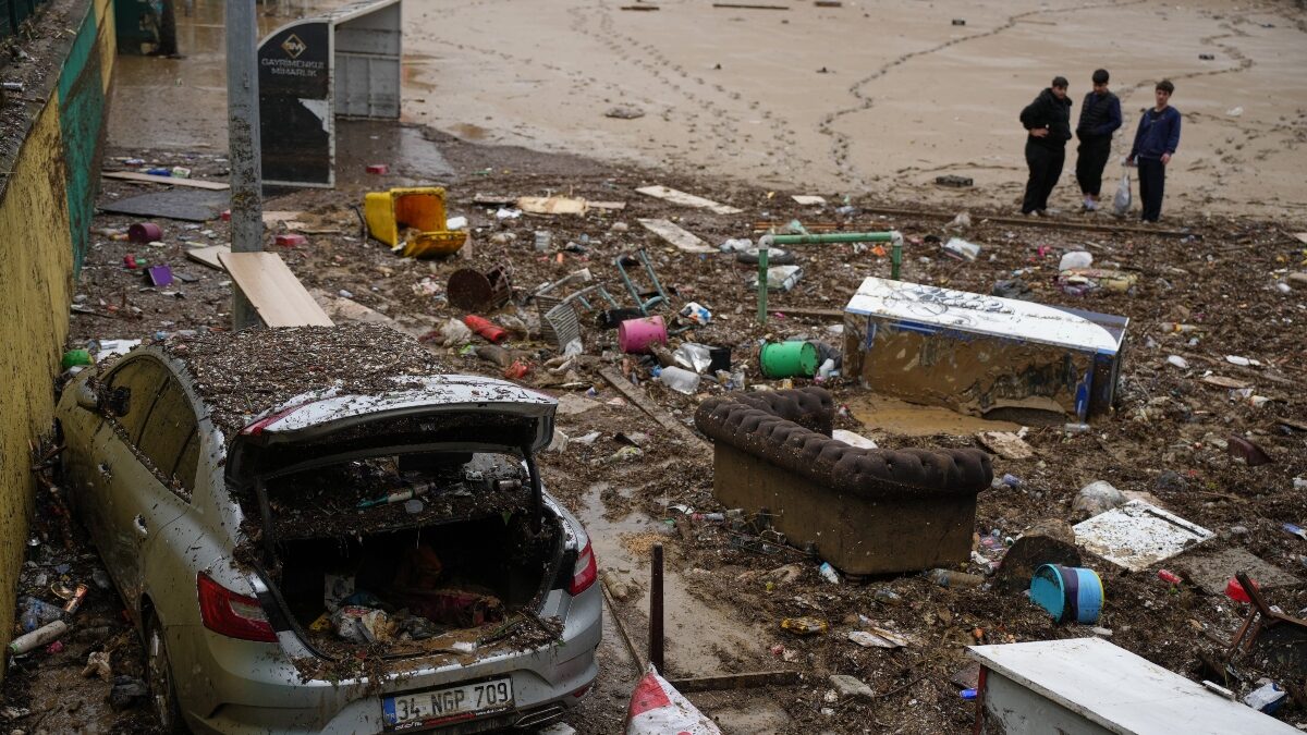 Local residents stand next to scattered vehicles and debris in the aftermath of floods caused by heavy rains, in Istanbul, Turkey, Thursday, Oct. 15, 2026.