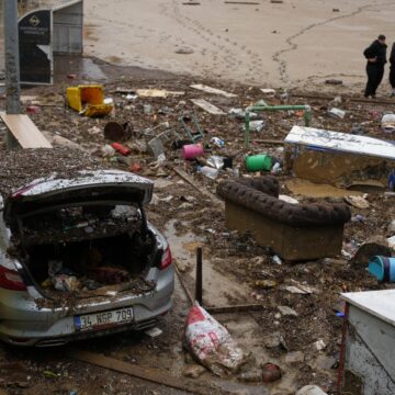 Local residents stand next to scattered vehicles and debris in the aftermath of floods caused by heavy rains, in Istanbul, Turkey, Thursday, Oct. 15, 2026.