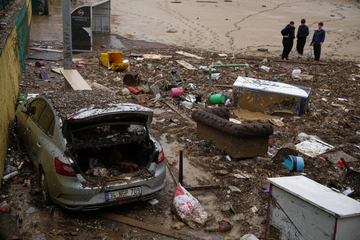 Local residents stand next to scattered vehicles and debris in the aftermath of floods caused by heavy rains, in Istanbul, Turkey, Thursday, Oct. 15, 2026.