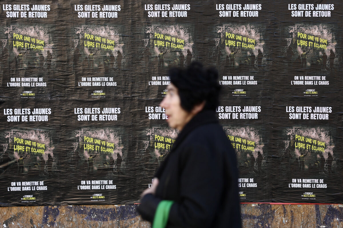 A woman walks past posters reading "The Yellow Vests are back. For a life of dignity, freedom, and enlightenment. We are going to restore order to the chaos" on a wall in Paris, France, October 14, 2026. REUTERS